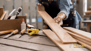 DIYer holding a plywood board at a home workshop bench